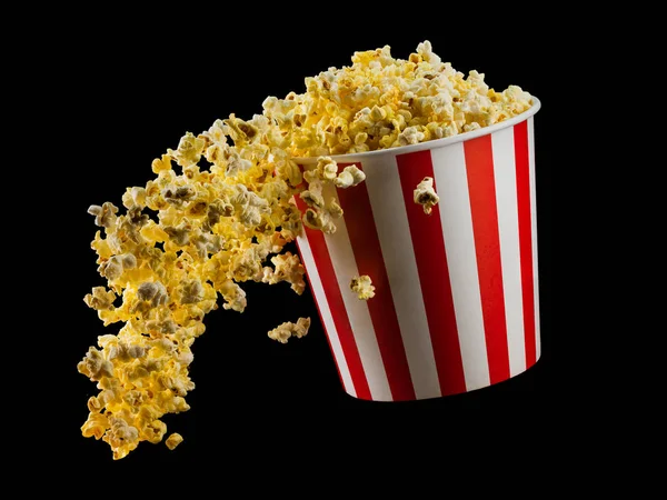 Létající popcorn z proužkované nádoby izolované na černém pozadí — Stock fotografie