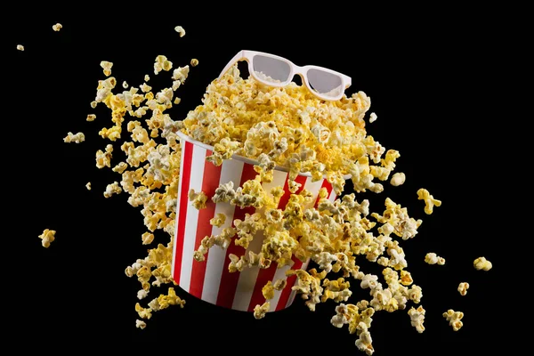 Fliegendes Popcorn aus gestreiftem Eimer isoliert auf schwarzem Hintergrund — Stockfoto