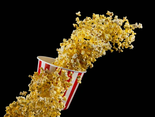 Fliegendes Popcorn aus gestreiftem Eimer isoliert auf schwarzem Hintergrund — Stockfoto