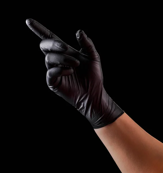 Hand in black gloves with index finger pointing or touching something on black — Stock Photo, Image