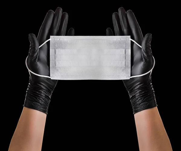 Ruka v černé rukavice na sobě jednorázové obličejové masky izolované na černém pozadí — Stock fotografie