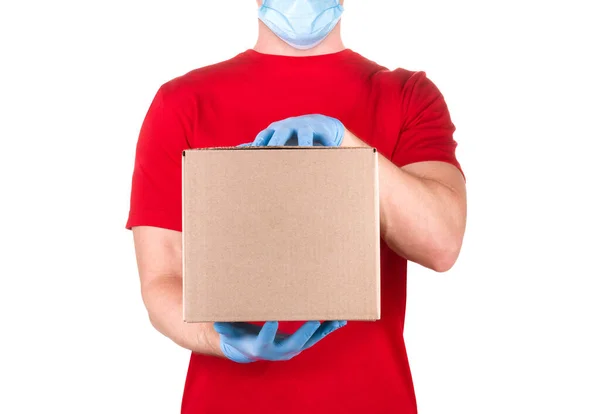 Hombre en camiseta roja y guante médico azul sosteniendo caja de cartón aislado blanco — Foto de Stock