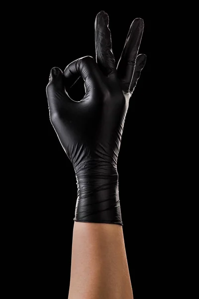 Hand in black gloves holding something with two fingers isolated on black — Stock Photo, Image