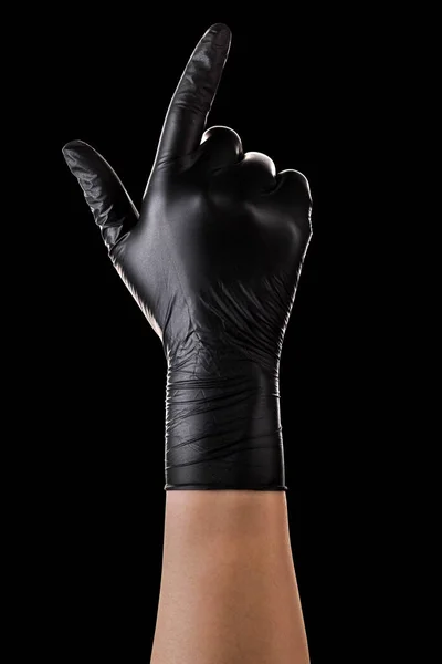 Hand in schwarzen Handschuhen, Zeigefinger nach oben auf schwarz — Stockfoto
