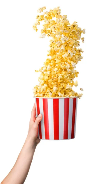 Woman hand holding striped bucket with flying popcorn isolated on white