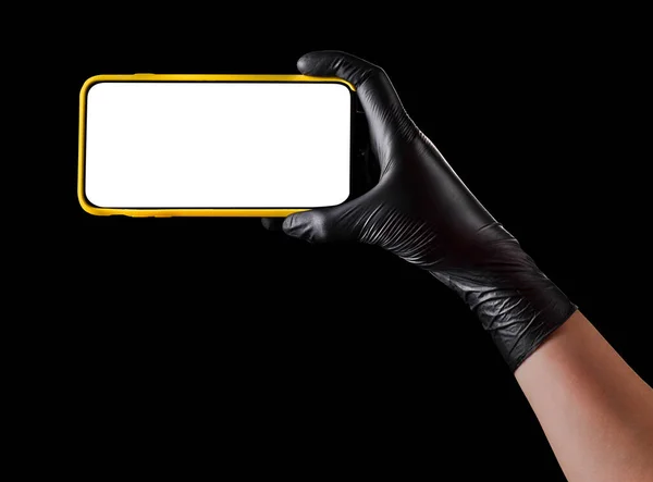 Hand in Hand schwarzer Handschuh hält Handy mit leerem Bildschirm isoliert auf schwarz — Stockfoto