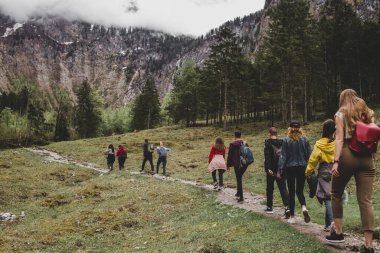 Rothbach Şelalesi 'ne yürüyüş yapan turist grubu, arka plandaki kayalıklara ve bulutlu gökyüzüne çam ormanı fırlatıyor. Bavyera 'da. Almanya