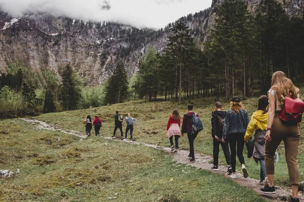 Rothbach Şelalesi 'ne yürüyüş yapan turist grubu, arka plandaki kayalıklara ve bulutlu gökyüzüne çam ormanı fırlatıyor. Bavyera 'da. Almanya