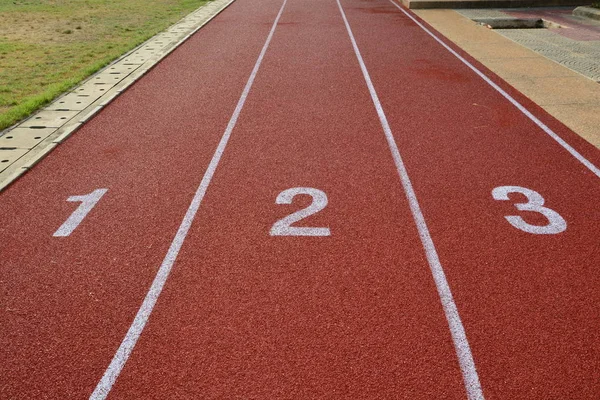 Red treadmill, track running at the stadium with green grass