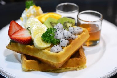 Beyaz bir tabaktabaktabaktabaktabaktabaktabaktabaktabaktabaktabaktabaktabaktabak meyve ve kırbaçlama kreması ile waffle