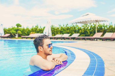 Adam havuz korkuluk üzerinde asılı dışarı bakar.