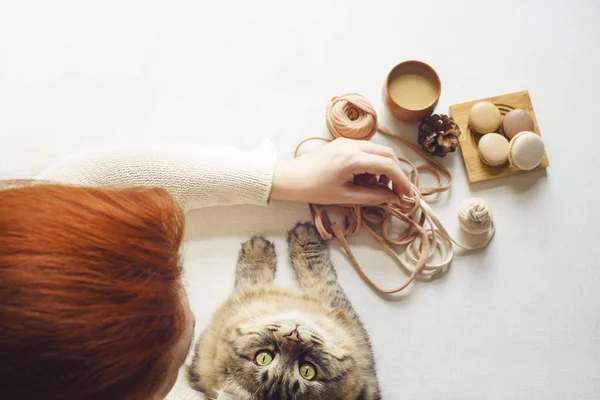 Cat looks up right to camera. Young woman with red hair drink latte — Stock Photo, Image