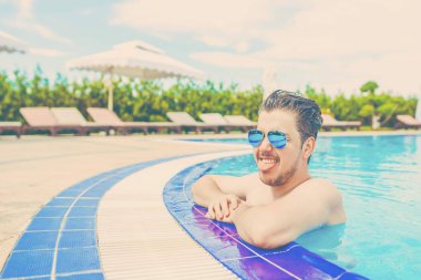 Havuzu, korkuluk üzerinde asılı dışarı bakan adam.