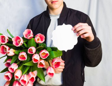 Buket laleler ve beyaz kağıt kartı tutan tanınmayan adam 