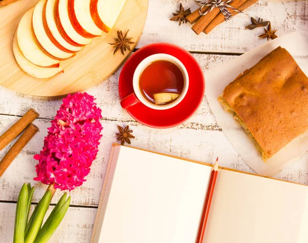 Notepad, apple, tea, flower  on wooden table