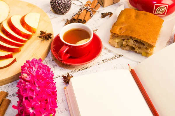 Notepad, apple, tea, flower  on wooden table