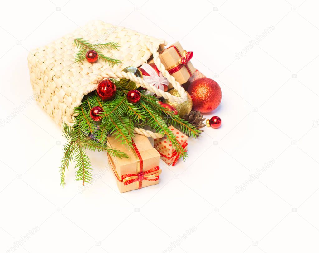 Christmas or New Year background: basket  with colored glass toys and balls, fir tree branches, decorations and gifts on white background.