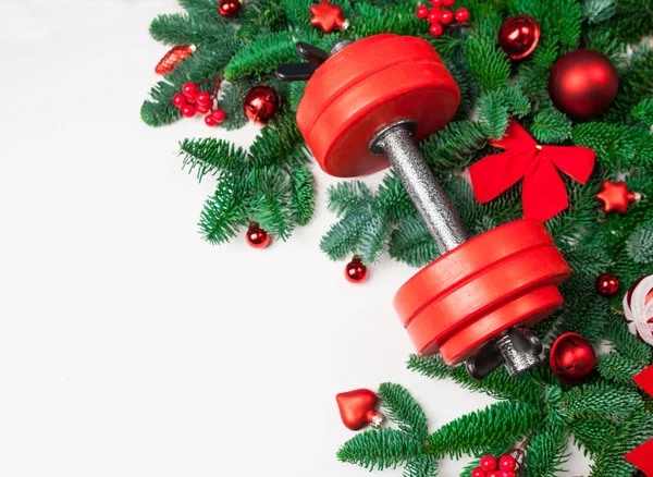 Noel ve yeni yıl arka plan: köknar ağacı dalları, kırmızı cam oyuncaklar, süslemeleri dumbbell ile beyaz bir arka plan üzerinde.