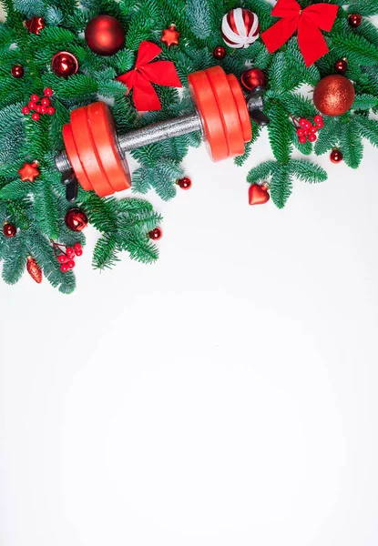 Noel ve yeni yıl arka plan: köknar ağacı dalları, kırmızı cam oyuncaklar, süslemeleri dumbbell ile beyaz bir arka plan üzerinde.