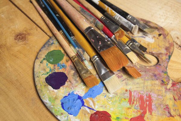 paint palette with brushes on wooden background  