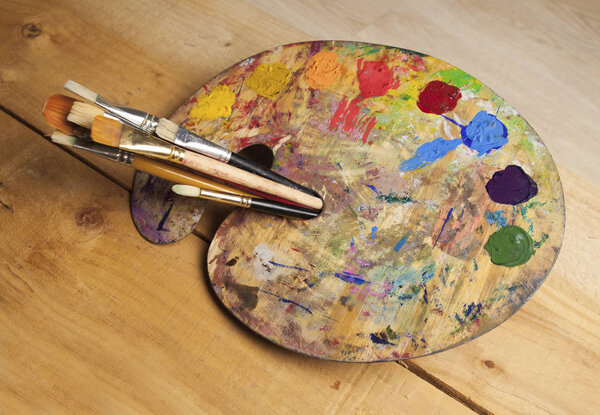 paint palette with brushes on wooden background  