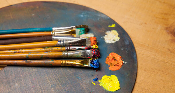 paint palette with brushes on wooden background  