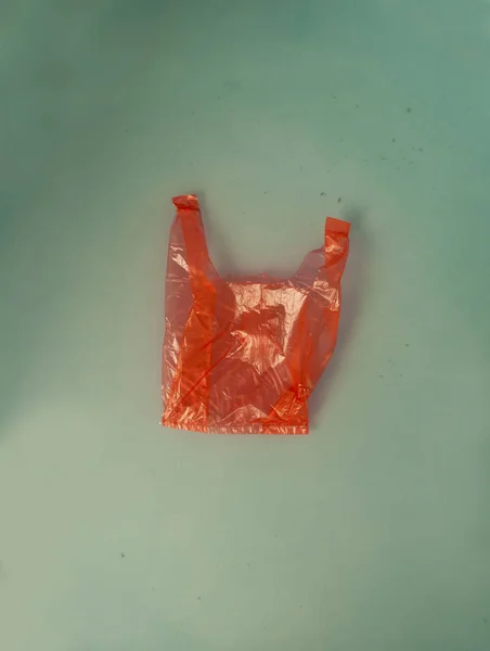 Ekoloji kavramı için su yüzeyindeki kırmızı plastik torba