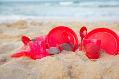 kumlu plajda kırmızı plastik bulaşık yakından görünümü