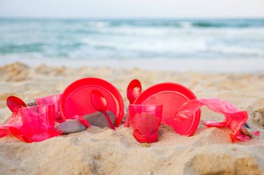 kumlu plajda kırmızı plastik bulaşık yakından görünümü