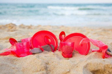 kumlu plajda kırmızı plastik bulaşık yakından görünümü