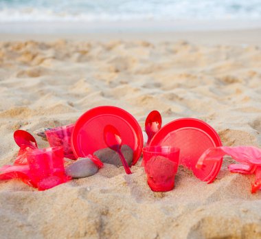 kumlu plajda kırmızı plastik bulaşık yakından görünümü