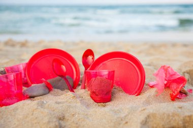 kumlu plajda kırmızı plastik bulaşık yakından görünümü