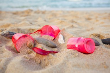 kumlu plajda kırmızı plastik bulaşık yakından görünümü