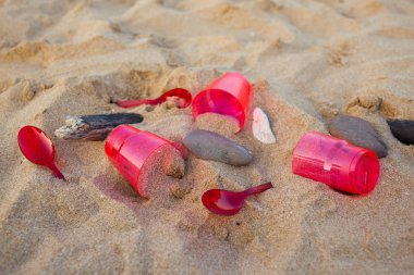 kumlu plajda kırmızı plastik bulaşık yakından görünümü