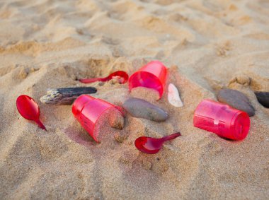 kumlu plajda kırmızı plastik bulaşık yakından görünümü