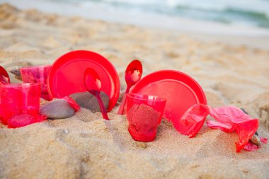 kumlu plajda kırmızı plastik bulaşık yakından görünümü