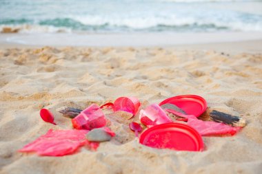 kumlu plajda kırmızı plastik bulaşık yakından görünümü