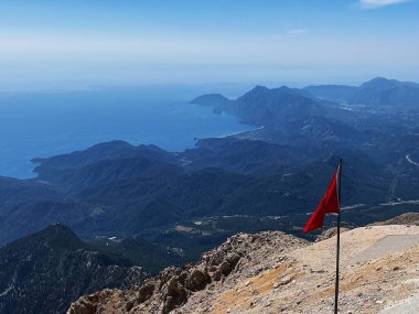 Türk bayrağı sisli deniz kıyısının arka planına karşı Tahtali Dağı 'nda dalgalanıyor. Akdeniz 'in manzarası. Olympos Teleferik, Tahtali 2365 metre, Kemer, Antalya.