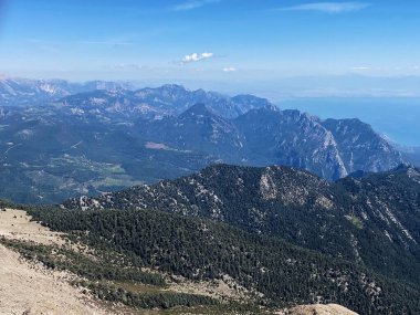 Dağların panoramik manzarası ve Tahtali 'nin zirvesinden Kemer kıyıları. Olympos Teleferik, Tahtali 2365 metre, Kemer, Antalya, Türkiye. Denizden gökyüzüne.