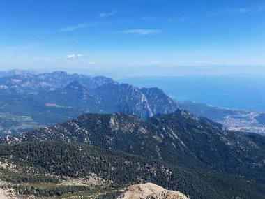 Dağların panoramik manzarası ve Tahtali 'nin zirvesinden Kemer kıyıları. Olympos Teleferik, Tahtali 2365 metre, Kemer, Antalya, Türkiye. Denizden gökyüzüne.