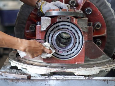 Bir teknisyenin diferansiyel teçhizat montajında yatağı temizlerken çekilmiş yakın plan bir fotoğraf. Bir atölyede otomotiv onarımı ve bakımının karmaşık sürecini vurguluyor..