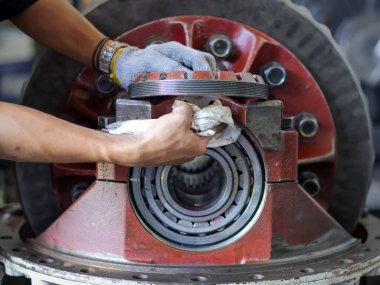 Bir teknisyenin diferansiyel teçhizat montajında yatağı temizlerken çekilmiş yakın plan bir fotoğraf. Bir atölyede otomotiv onarımı ve bakımının karmaşık sürecini vurguluyor..