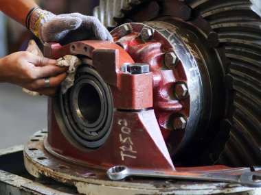 Bir teknisyenin diferansiyel teçhizat montajında yatağı temizlerken çekilmiş yakın plan bir fotoğraf. Bir atölyede otomotiv onarımı ve bakımının karmaşık sürecini vurguluyor..