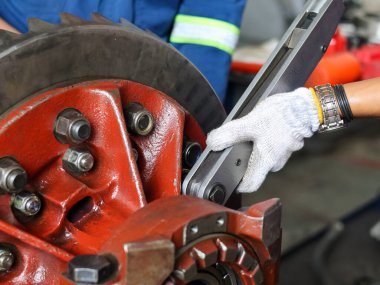 Bir tamirci diferansiyel başlık dişlilerinin vidalarını sıkmak için büyük bir tork anahtarı kullanır, endüstriyel onarım ve makine bakımını gösterir..