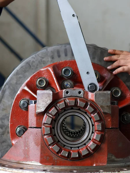 Bir tamirci diferansiyel başlık dişlilerinin vidalarını sıkmak için büyük bir tork anahtarı kullanır, endüstriyel onarım ve makine bakımını gösterir..