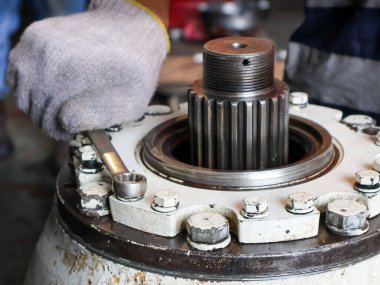 Ağır bir endüstriyel makinenin vidalarını sıkmak için İngiliz anahtarı ya da İngiliz anahtarı kullanan eldivenli bir elin yakın çekimi.