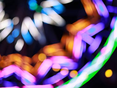 Dönme dolabın gece karanlığındaki renkli ışıkların güzel bir odak kaybı ya da bokeh etkisi, çeşitli renklerde, koyu bir arka plana karşı soyut, rüya gibi ışık çemberleri oluşturur..