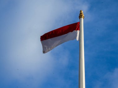 Endonezya ulusal bayrağı açık mavi gökyüzüne karşı uzun direkte dalgalanıyor