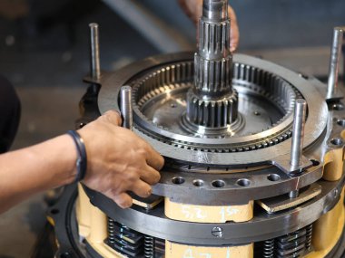 Eldivenli işçiler atölyede hassas aletlerle endüstriyel debriyaj mekanizması monte ediyorlar..