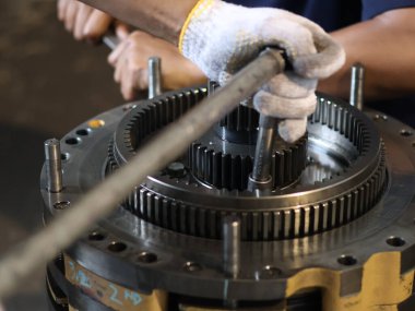 Şanzıman üzerinde çalışan bir insanın elleri, uzun saplı ve endüstriyel ayarlarla cıvatayı sıkma sürecini vurguluyor..